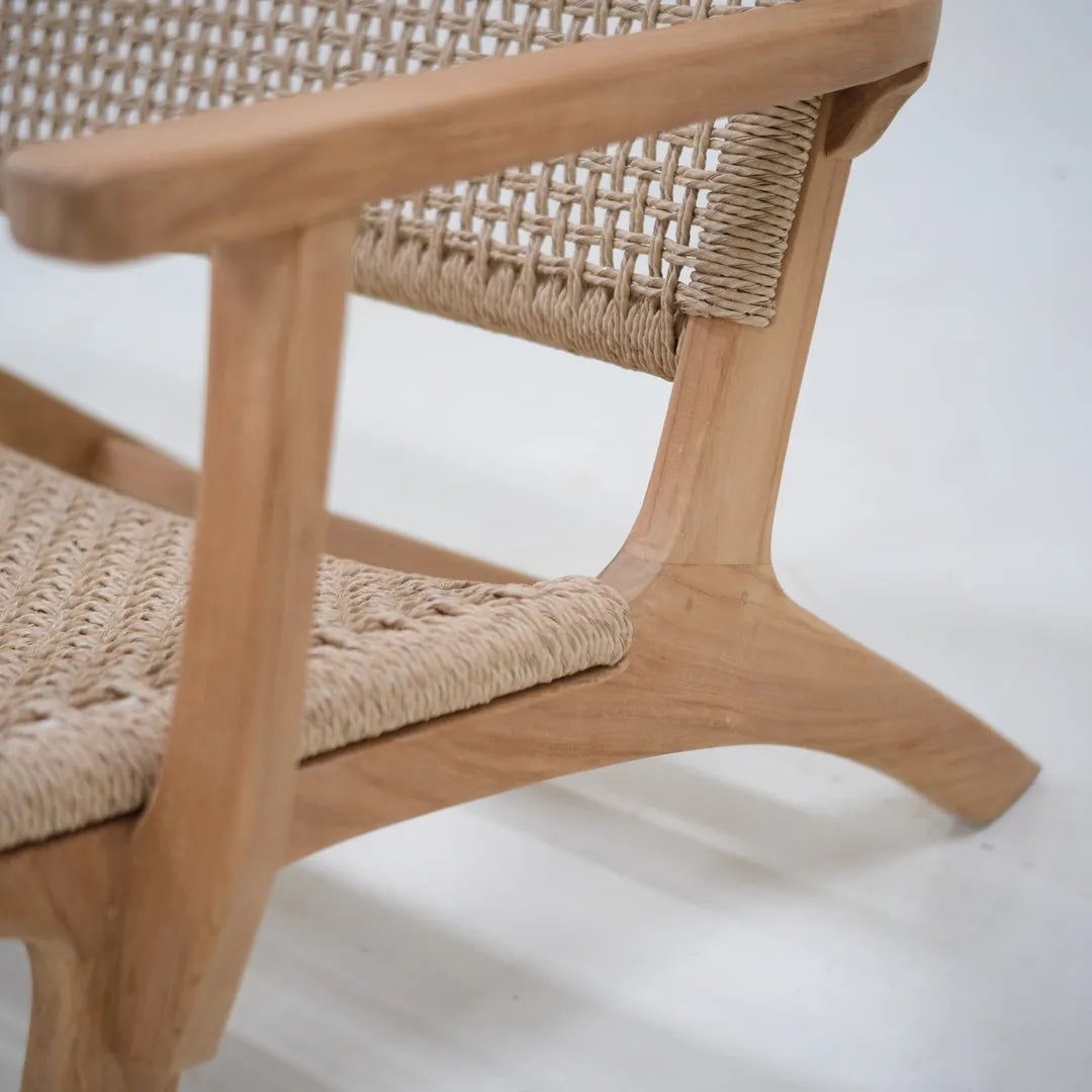 Primer plano del reposabrazos de teca del sillón lounge Tropézienne y del asiento de ratán tejido a mano.