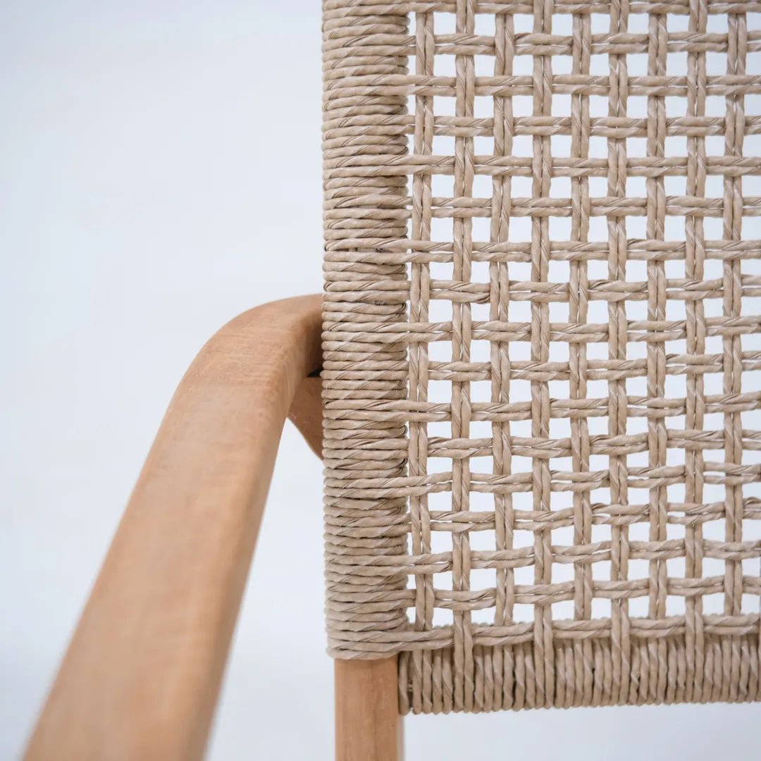 Primer plano del reposabrazos de teca del sillón lounge Tropézienne y del asiento de ratán tejido a mano.