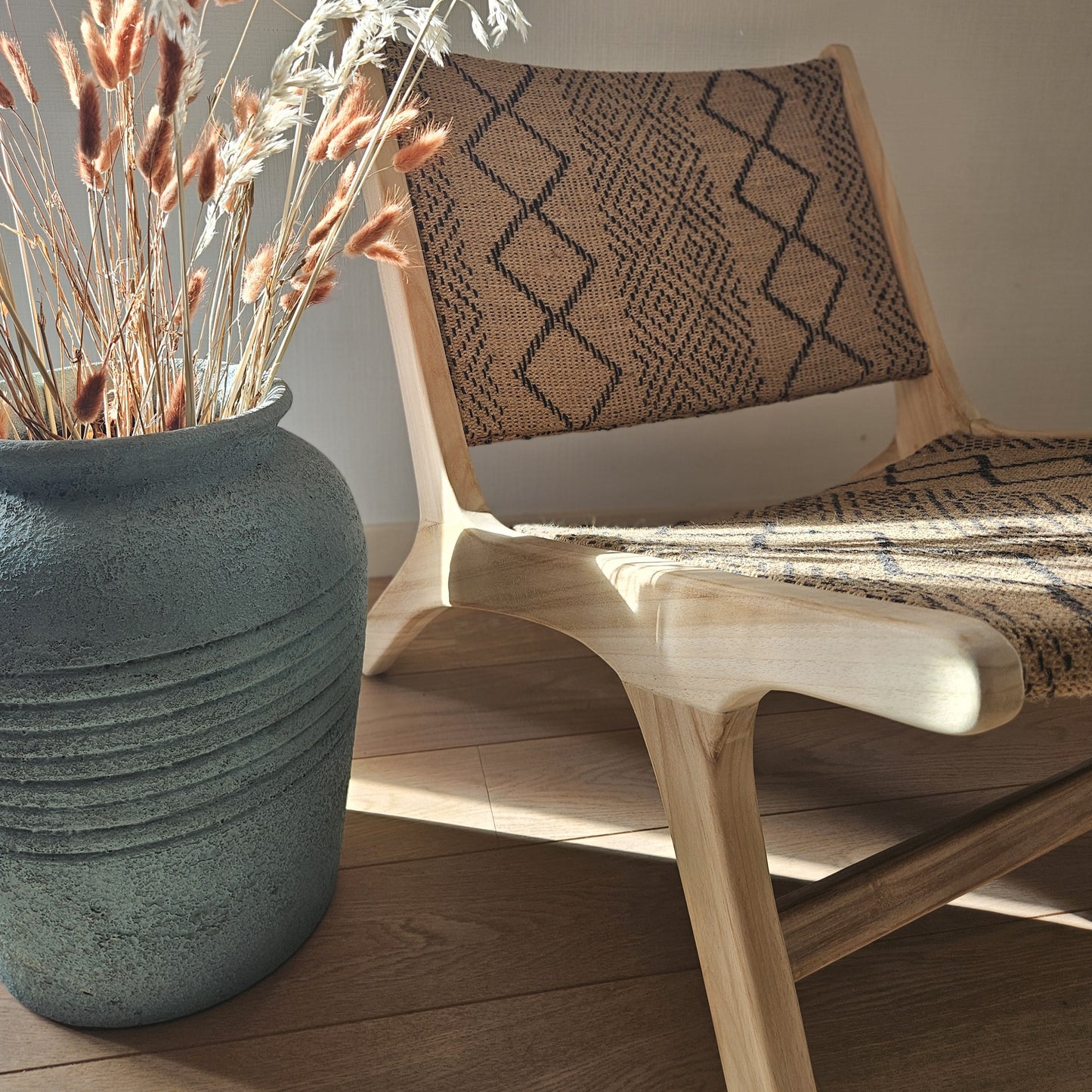 Close-up of the Funchal lounge chair showcasing its handcrafted teak wood frame and woven textile seat with geometric patterns.