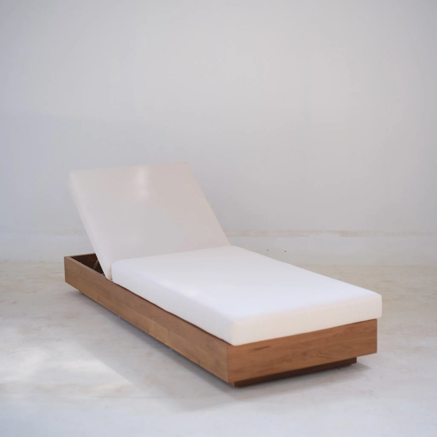 Laguna Sun Bed in teak with adjustable backrest and white cushion, angled view in natural light.