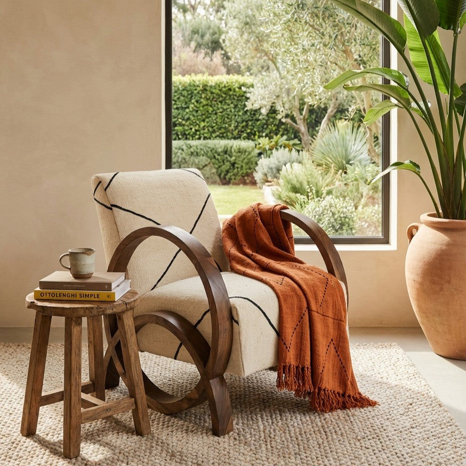 Ibiza style interior with a Moroccan lounge chair featuring a handmade Beni Ouarain seat, natural wood frame, warm earth tones and a calm slow living atmosphere connected to the garden.