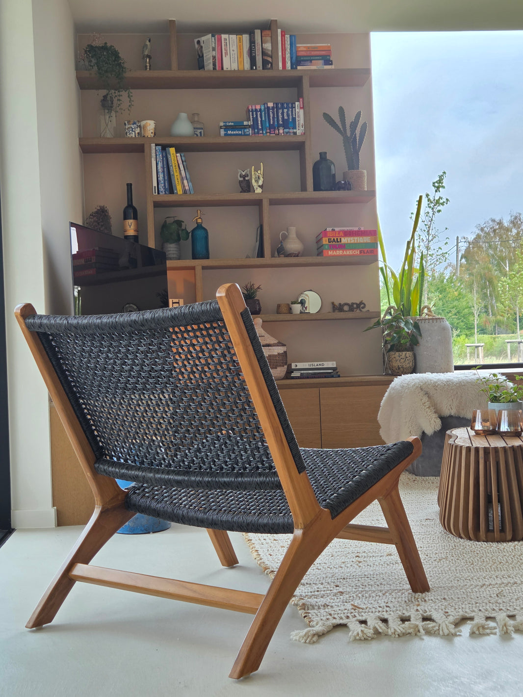 Dos sillones lounge outdoor tejidos en un balcón de madera con vistas a un tranquilo paisaje residencial, creando un refugio outdoor relajado y natural.