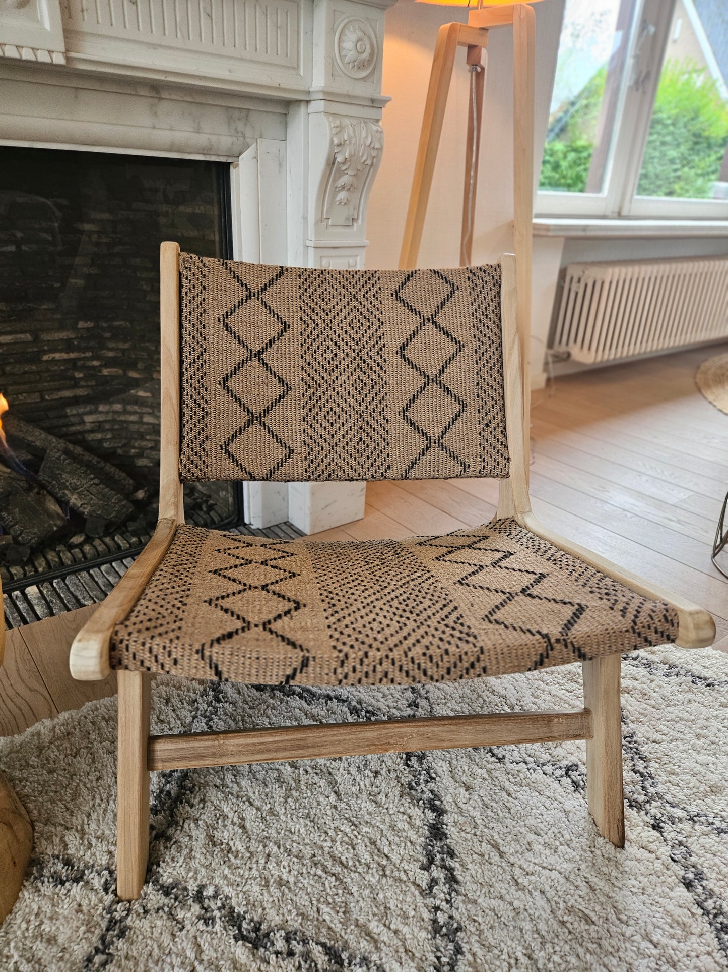 Funchal teak lounge chair with woven textile seat, styled on a Moroccan Beni Ouarain rug in a warm contemporary living space.