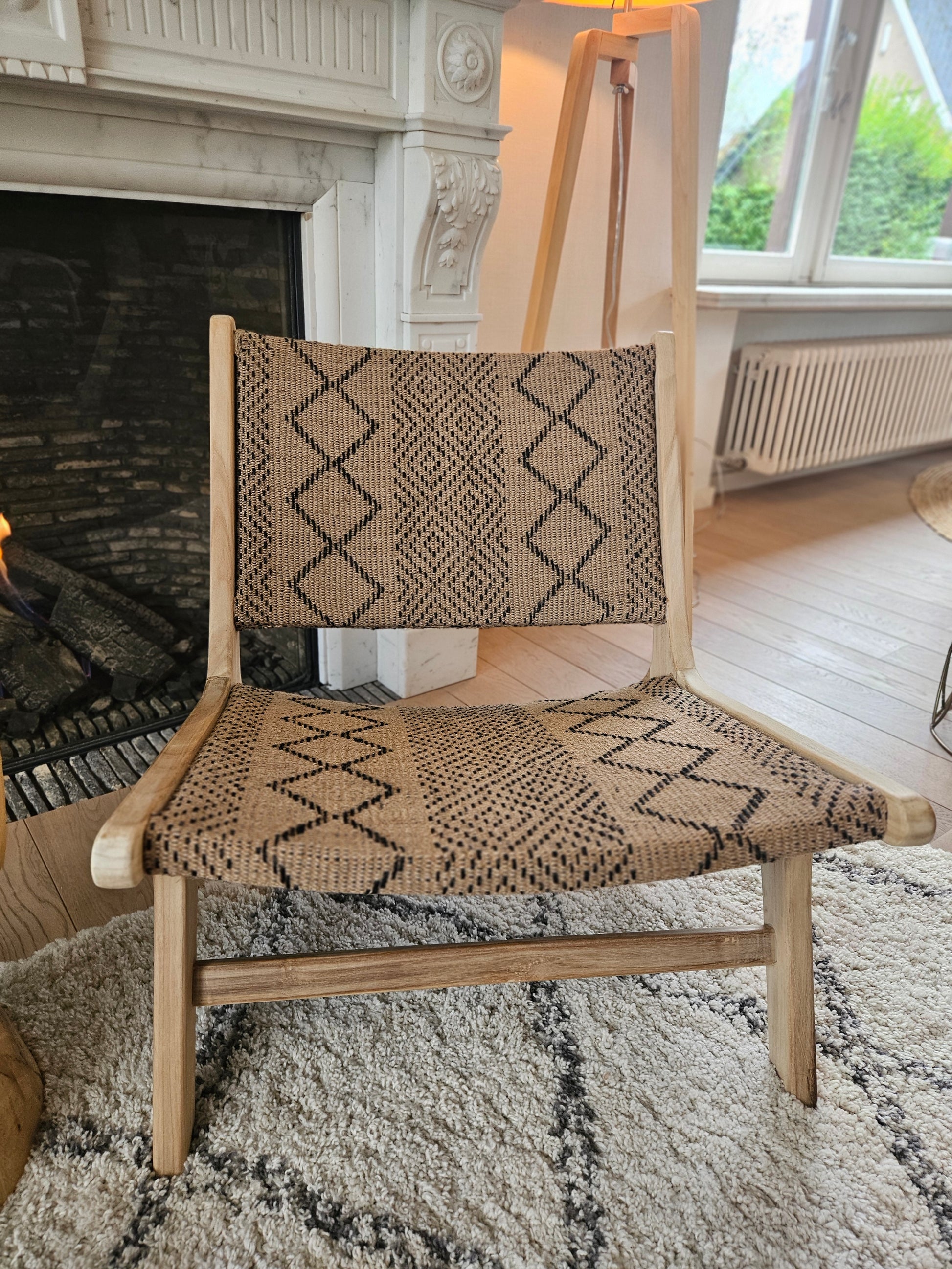 Funchal teak lounge chair with woven textile seat, styled on a Moroccan Beni Ouarain rug in a warm contemporary living space.