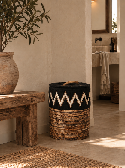 Black and natural woven storage basket with a decorative cream zigzag pattern and rope handle, styled in a warm Mediterranean interior