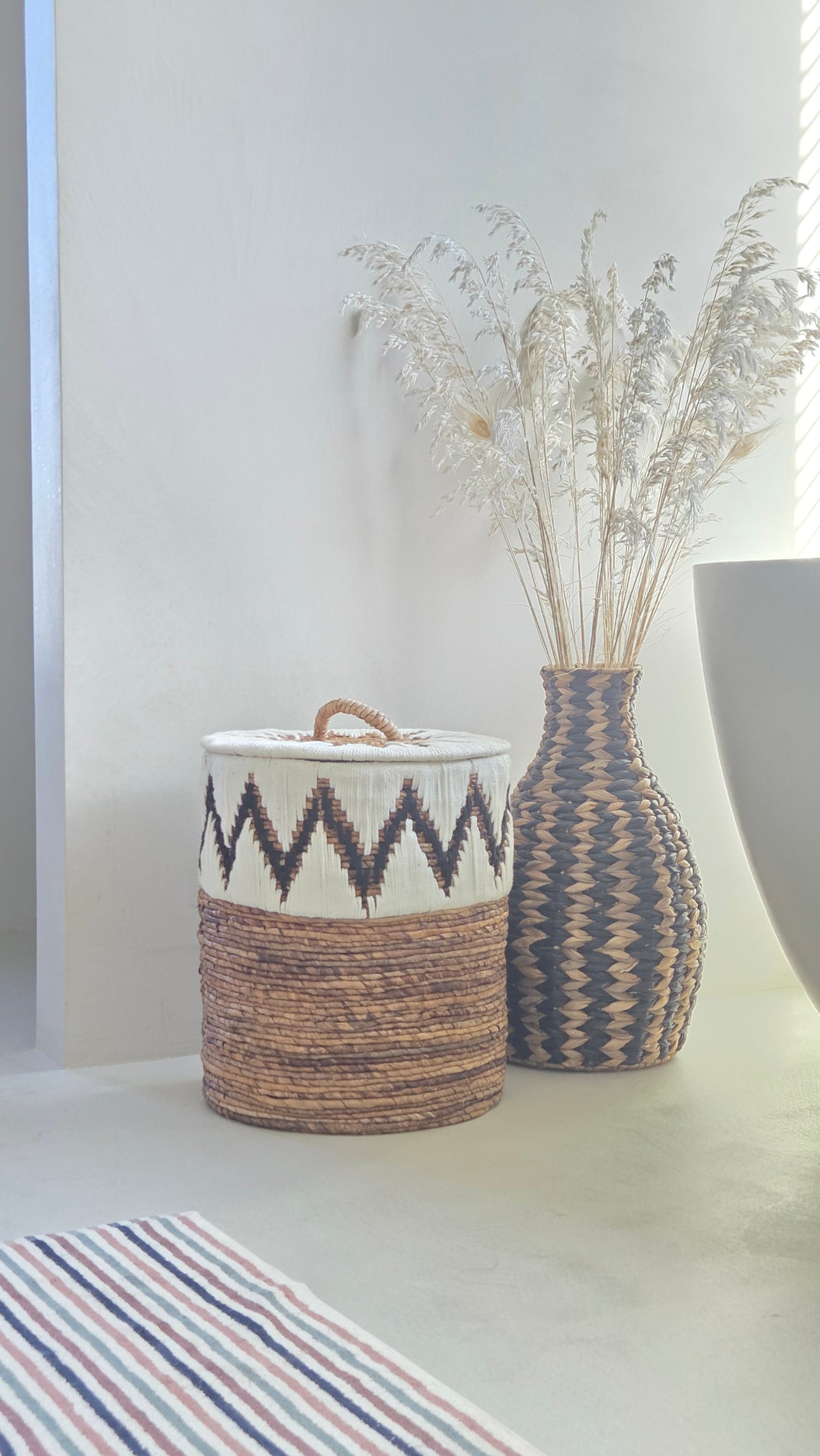 Samuel natural abaca storage basket with lid and white and black zigzag pattern in a boho bathroom.