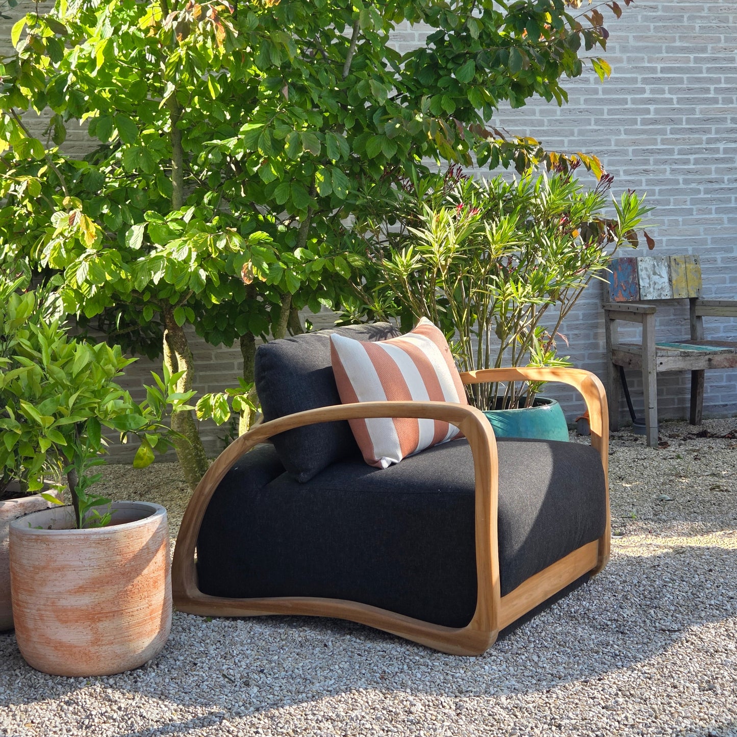 Elegant Adrian lounge chair crafted from Grade A teak, creating a relaxed Mediterranean outdoor living atmosphere surrounded by natural greenery