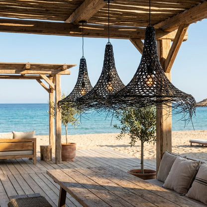Ibiza style outdoor dining area with handcrafted woven pendant lights, rustic wooden pergola and sea view by the beach.