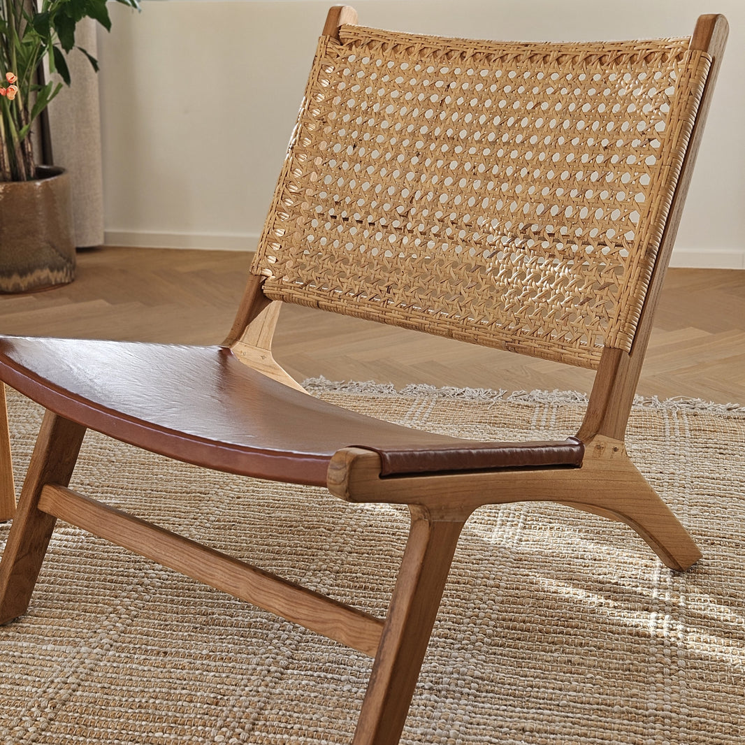 Stylish wooden lounge chair with a natural leather seat in a Mediterranean setting