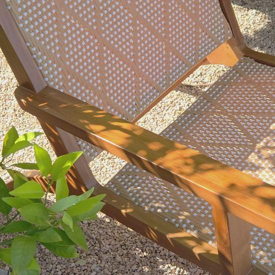 Lifestyle video featuring a handcrafted teak lounge outdoor chair with woven detailing, creating a relaxed Mediterranean-inspired outdoor atmosphere