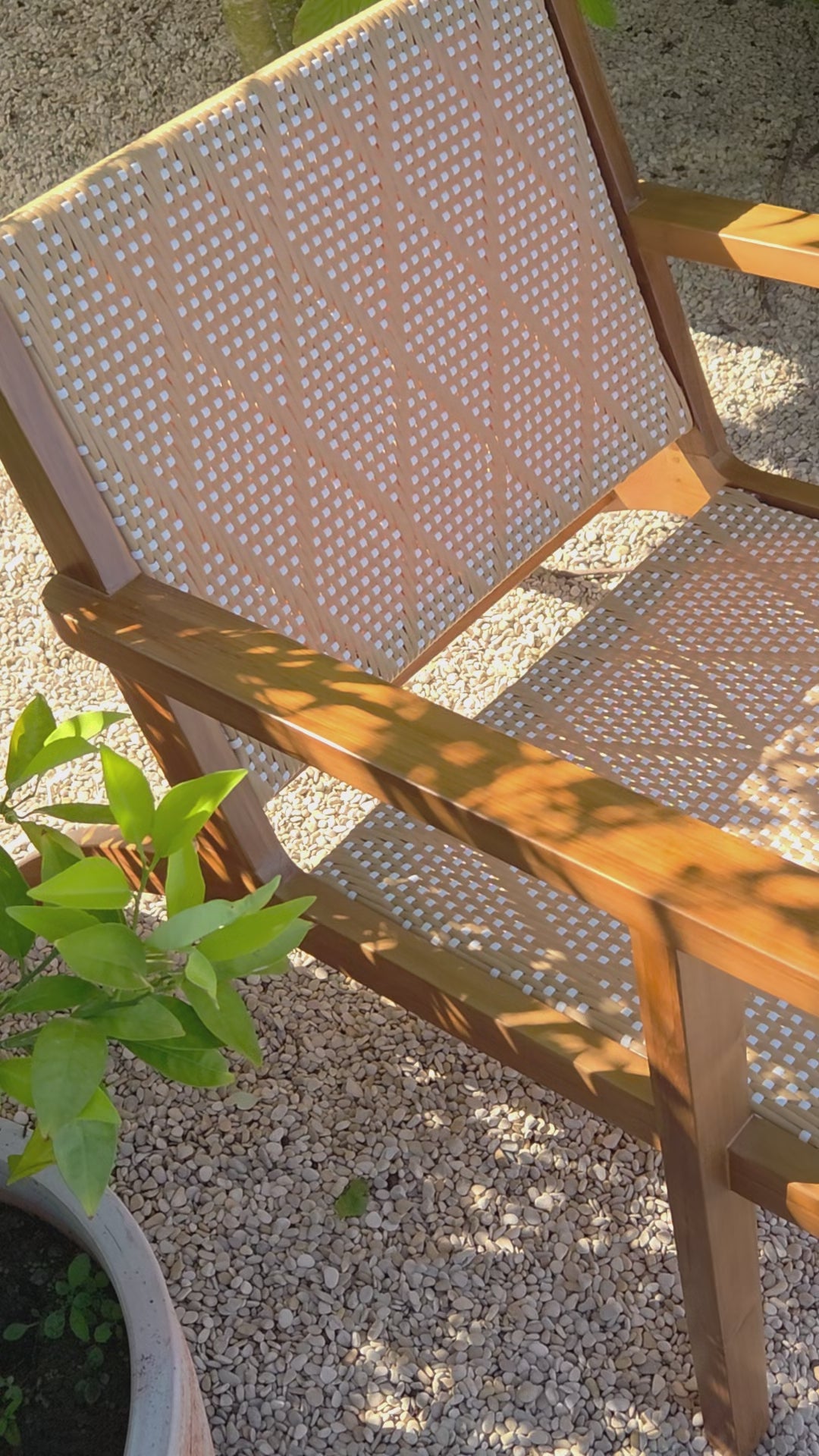 Lifestyle video featuring a handcrafted teak lounge outdoor chair with woven detailing, creating a relaxed Mediterranean-inspired outdoor atmosphere