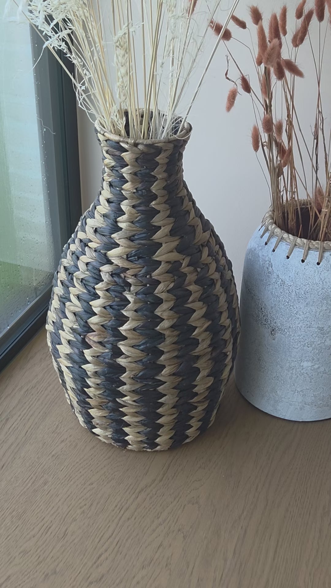 Zahara decorative woven vase featuring a striking black and natural zigzag pattern, styled with dried grasses. A textured statement piece that brings warmth and character to bohemian and contemporary interiors.